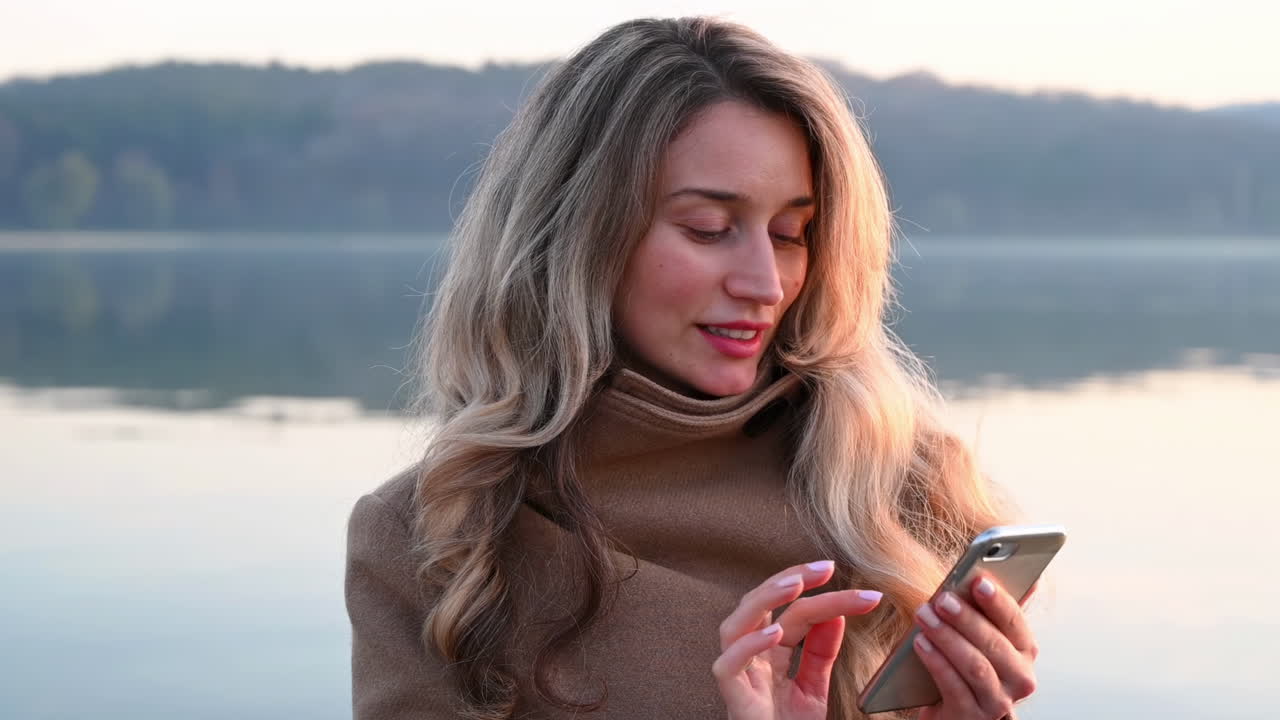 Lächelnde Frau, die im Park auf ihr Handy schaut