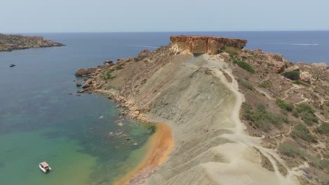 Clay-Cliffs-With-Flat-Top-Rock-Formation-In-The-Background-Along-Qarraba-Bay,-Mgarr-Malta