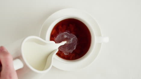 pouring milk into a cup of coffee