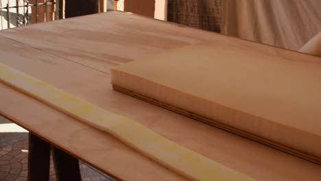 applying glue with a spray gun to sponges on a wood table -pan right