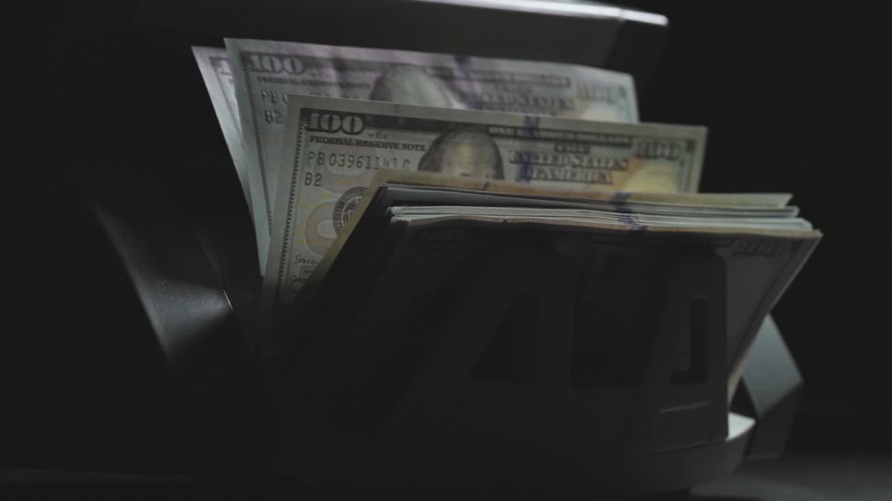 disparo en cámara lenta de la máquina de contar dinero para dinero de papel. economía de la sombra, concepto de evasión de impuestos. cálculo de billetes de cien dólares estadounidenses, cambio de divisas. luz de fondo, fondo negro