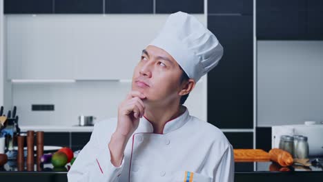 close up of asian man chef thinking about something and looking around while standing in home kitchen