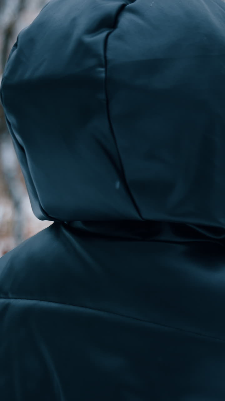 Lady in black blazer walks with paper cup in the park. Woman answers the phone and continues to walk. Vertical video