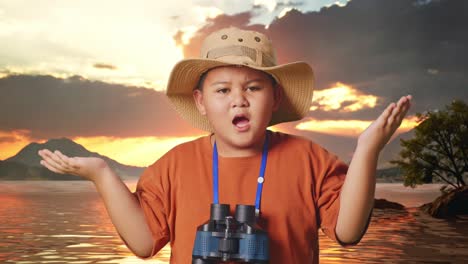 asian boy with a hat standing doubtfully and asking why after looking through the binoculars. boy researcher examines something at a lake, travel adventure concept, close up