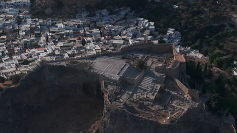 dolly back pan up aerial shot of the lindos acropolis