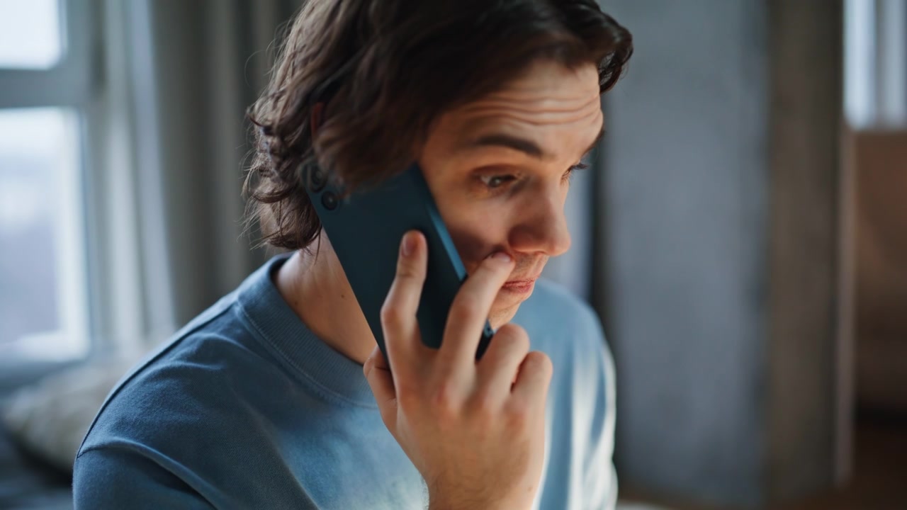 Young online worker calling smartphone using laptop touchpad at bedroom closeup
