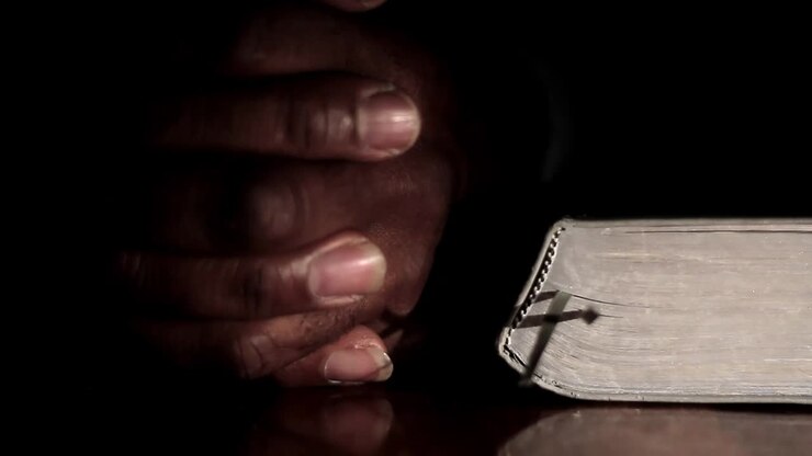 Preghiera a Dio con la mano sulla Bibbia, sfondo bianco, filmato stock con persone