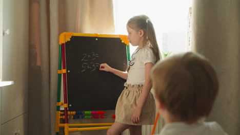 Girl-writes-on-blackboard-with-tiny-piece-of-chalk