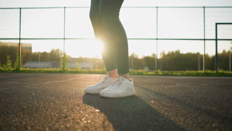 side low angle view of athlete bouncing volleyball, stepping forward with sunlight creating a golden glow on ground, preparing for serve or play during volleyball practice in outdoor court