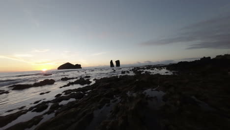 Low-fast-FPV-drone-shot-by-rocky-ocean-coast-at-Azores-at-sunset