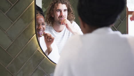 una pareja diversa, una joven afroamericana y un joven caucásico, se cepillan los dientes juntos.