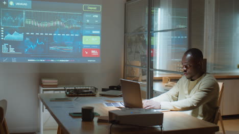 comerciante afroamericano trabajando en una computadora portátil en la oficina por la noche