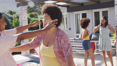 felices amigas diversas abrazándose y hablando en la fiesta de la piscina