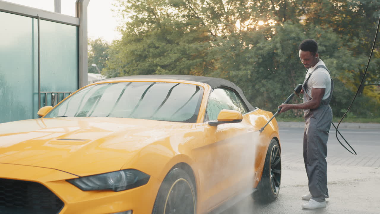 hombre lavando un coche convertible amarillo en un lavado de coches