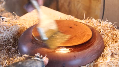 woodworker works with dish in workshop.