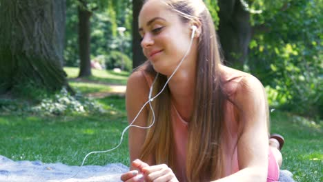 beautiful young woman with headphones relaxing in the park and listening to the music