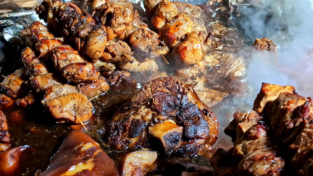 Various cuts of grilled and roasted meat sizzling and steaming on hot surface