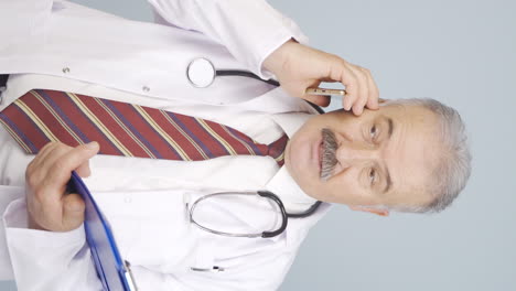 vídeo vertical del viejo médico está hablando por teléfono.