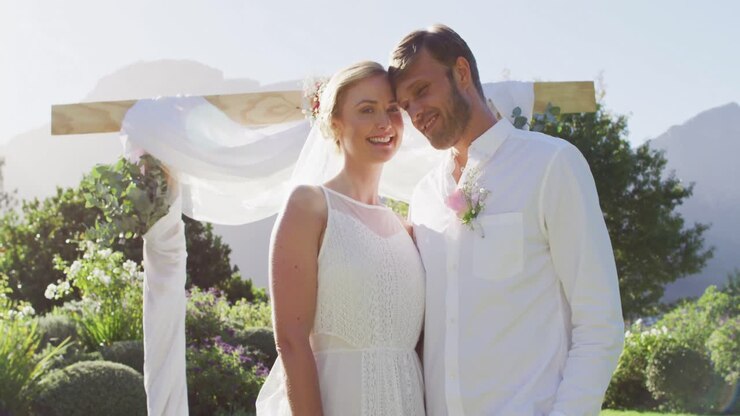 Portrait of happy caucasian newly wed couple, standing at altar outdoors