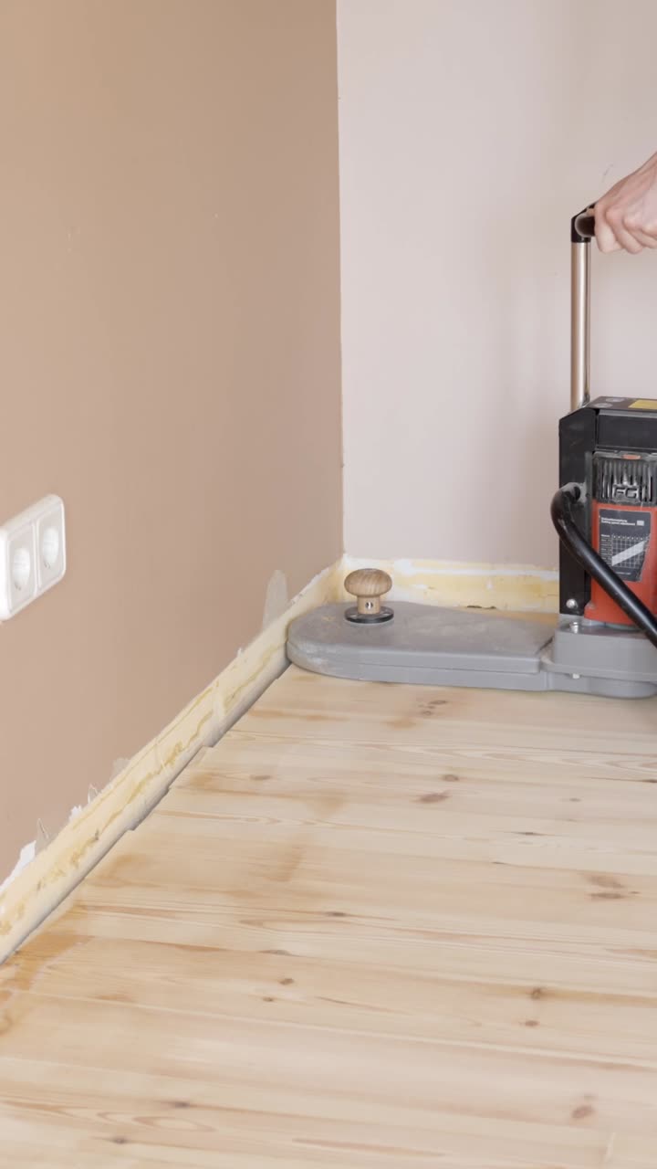 Vertical View Of High-Powered Floor Sander Machine Operating Near Wall. Close-up Shot