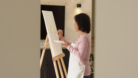 senior woman painting on canvas at home, enjoying creative solitude