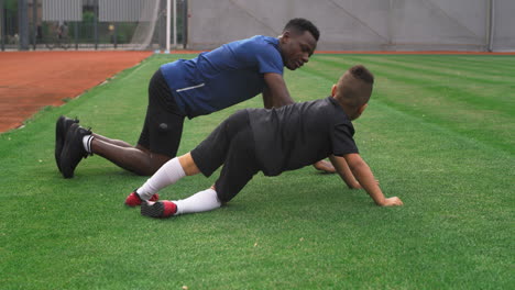 man and child doing push ups on football field