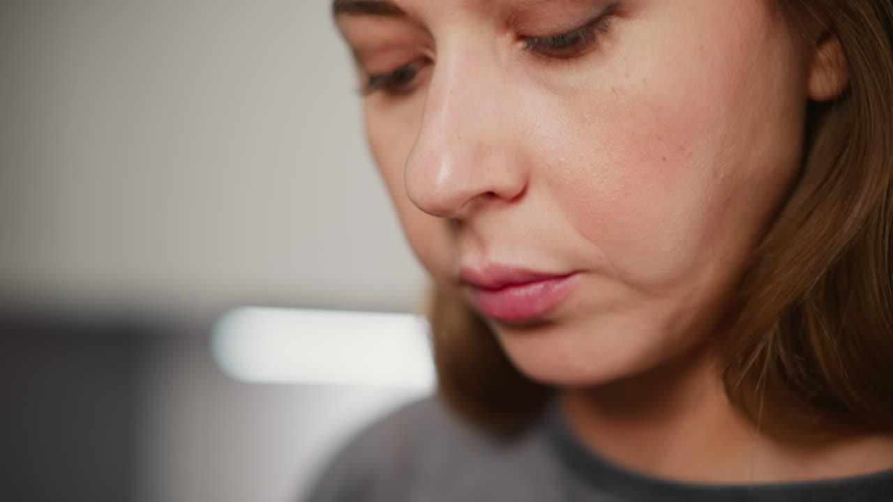 Extreme close-up of woman with glossy painted lips gently eating meat using chopsticks in bright modern kitchen, highlighting texture of skin
