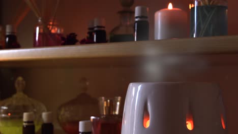 perfume making room with lots of candles flasks and glasses with colored liquids, near a steamer with steam coming out, and dust flying around