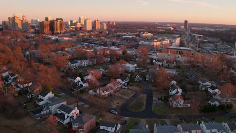 Aerial-pan-of-downtown-city-skyline-over-to-a-highway-and-a-sunset-over-a-high-school-football-field