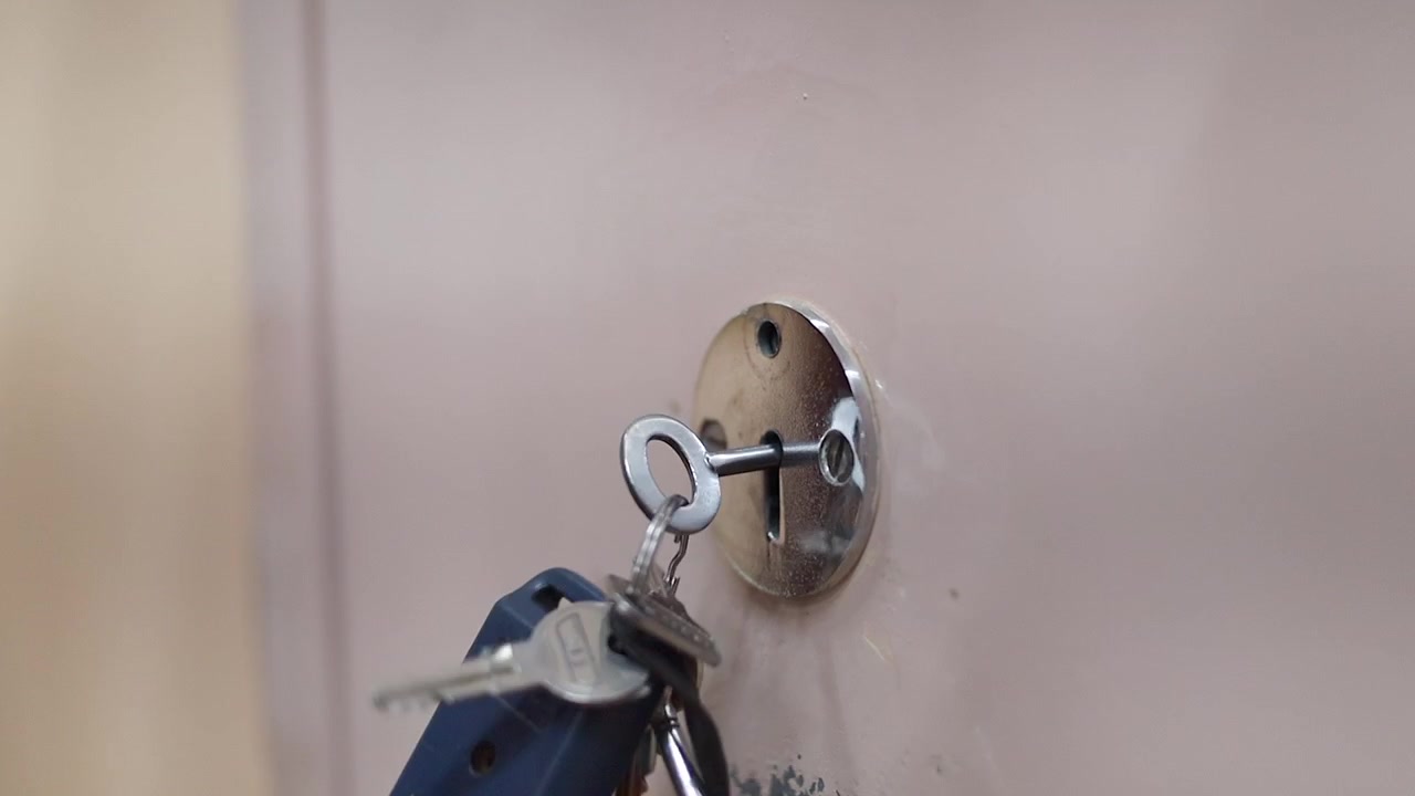 Large modern skeleton key is used to lock weathered steel door