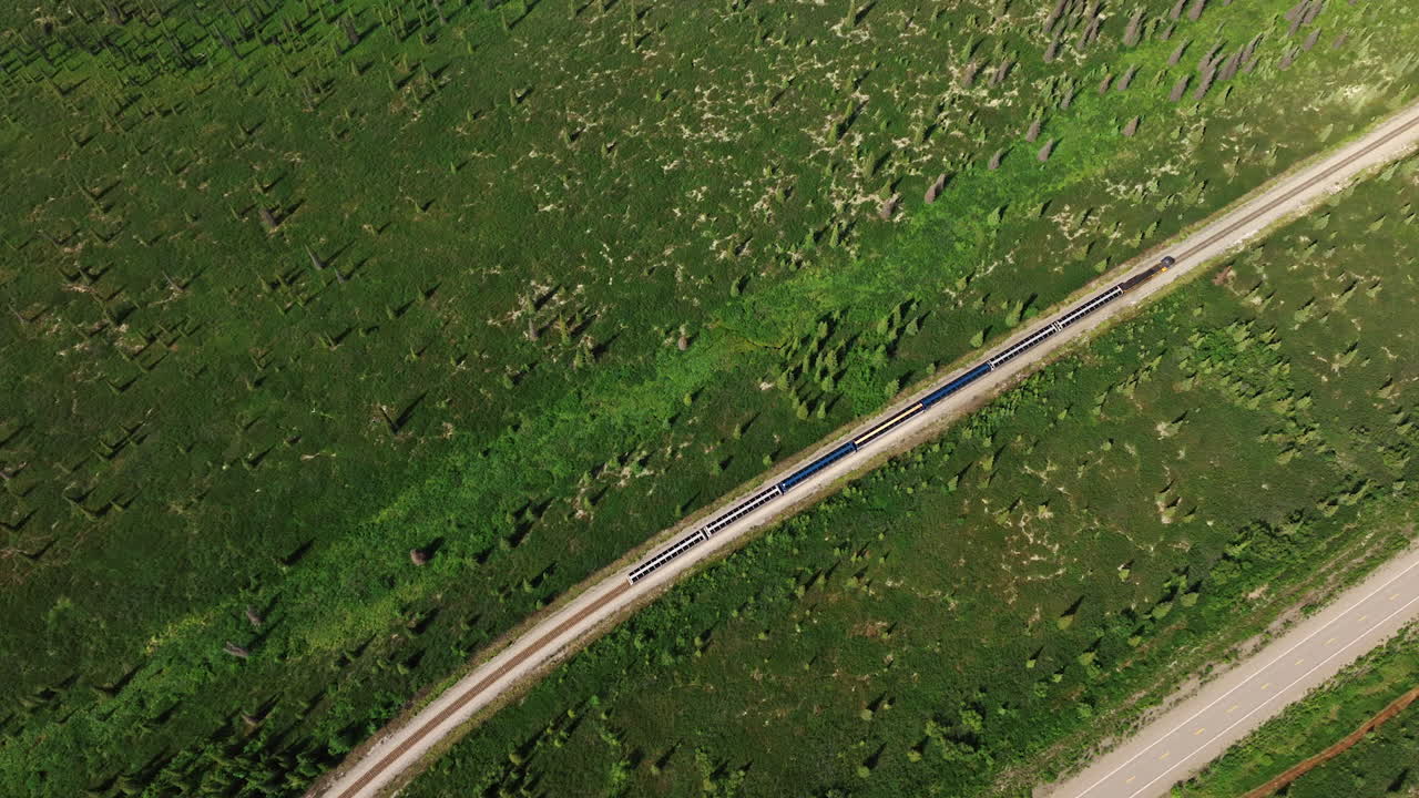Fast train moving quickly by the railways in the valley. Top view on the transport in Alaska