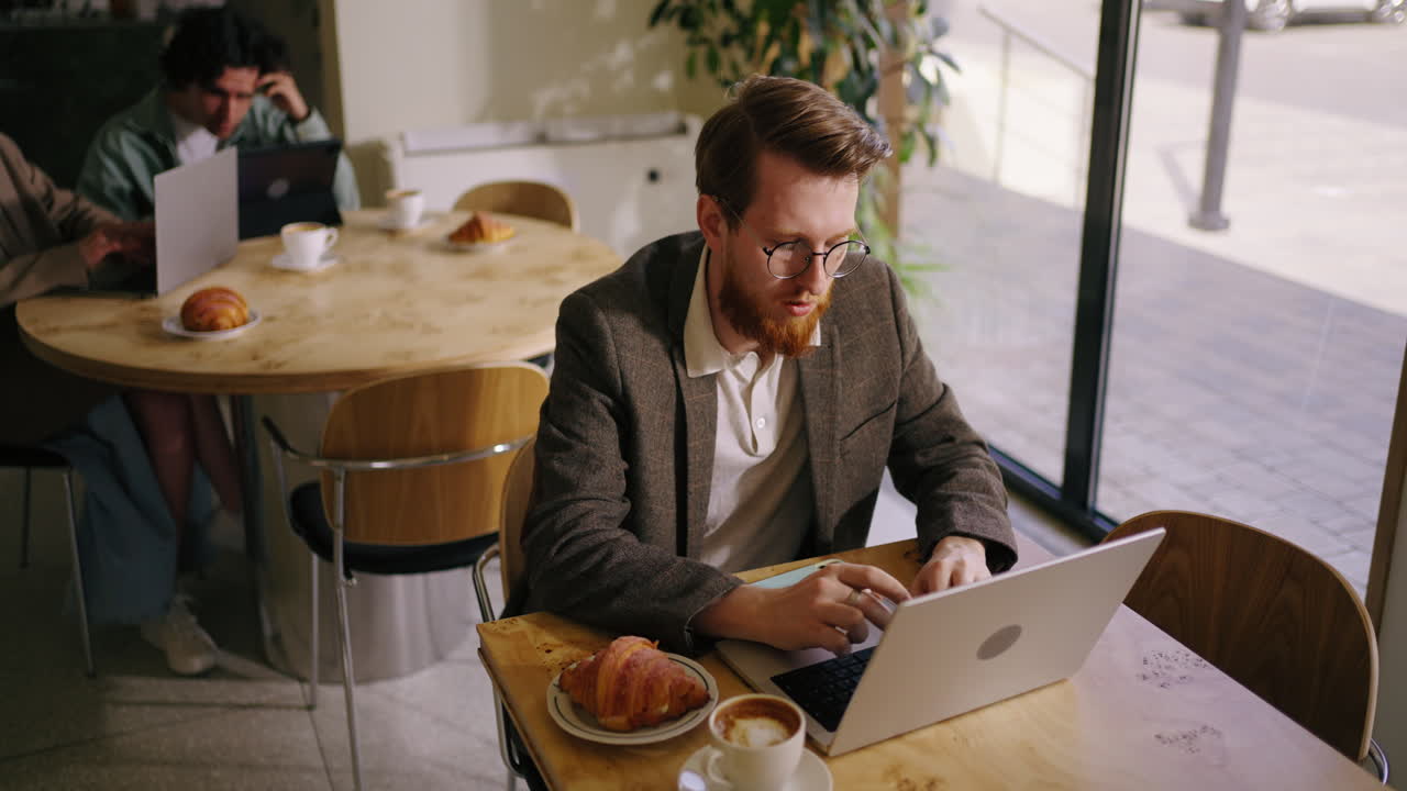 Uomo che lavora al portatile in un caffè