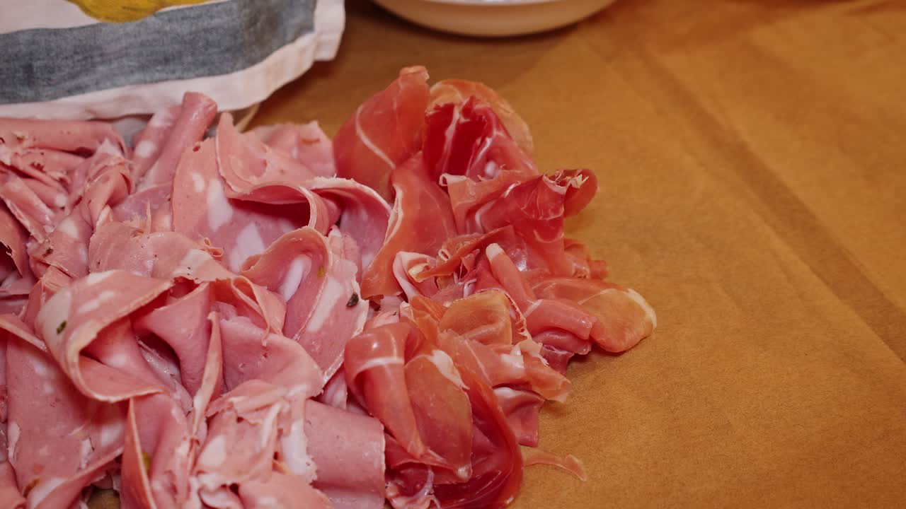 el chef decora la mesa con porciones de carne de jamón de parma por la noche