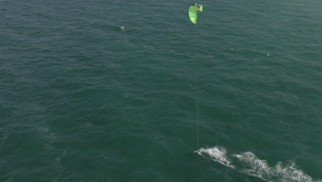 vista aérea de kite surfista disfrutando de un día ventoso en el agua verde del océano