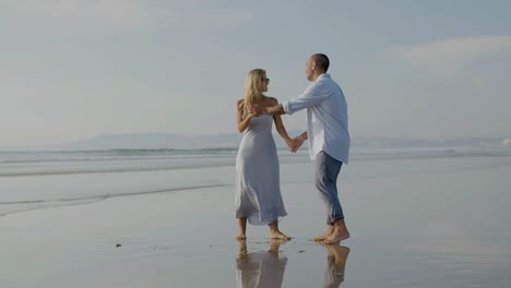 Beautiful-young-couple-dancing-at-seashore,-spending-time.