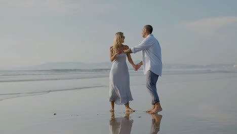 una hermosa pareja de jóvenes bailando en la orilla del mar, pasando el tiempo.