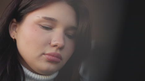 close-up of woman with pink lips focusing on something in front of her, softly illuminated with blurred background, showcasing her gentle expression and attention