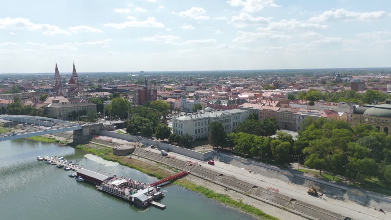 Panoramatický let dronu nad řekou Tisou, zachycující Szegediho muzeum Ference Móry a klidnou atmosféru na břehu řeky