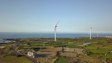 drone footage circling a wind turbine in a field on jeju island, south korea.