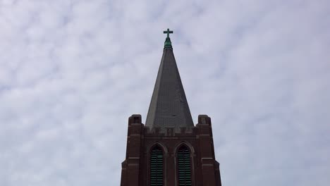 timelapse of old church steeple with crucifix and white clouds