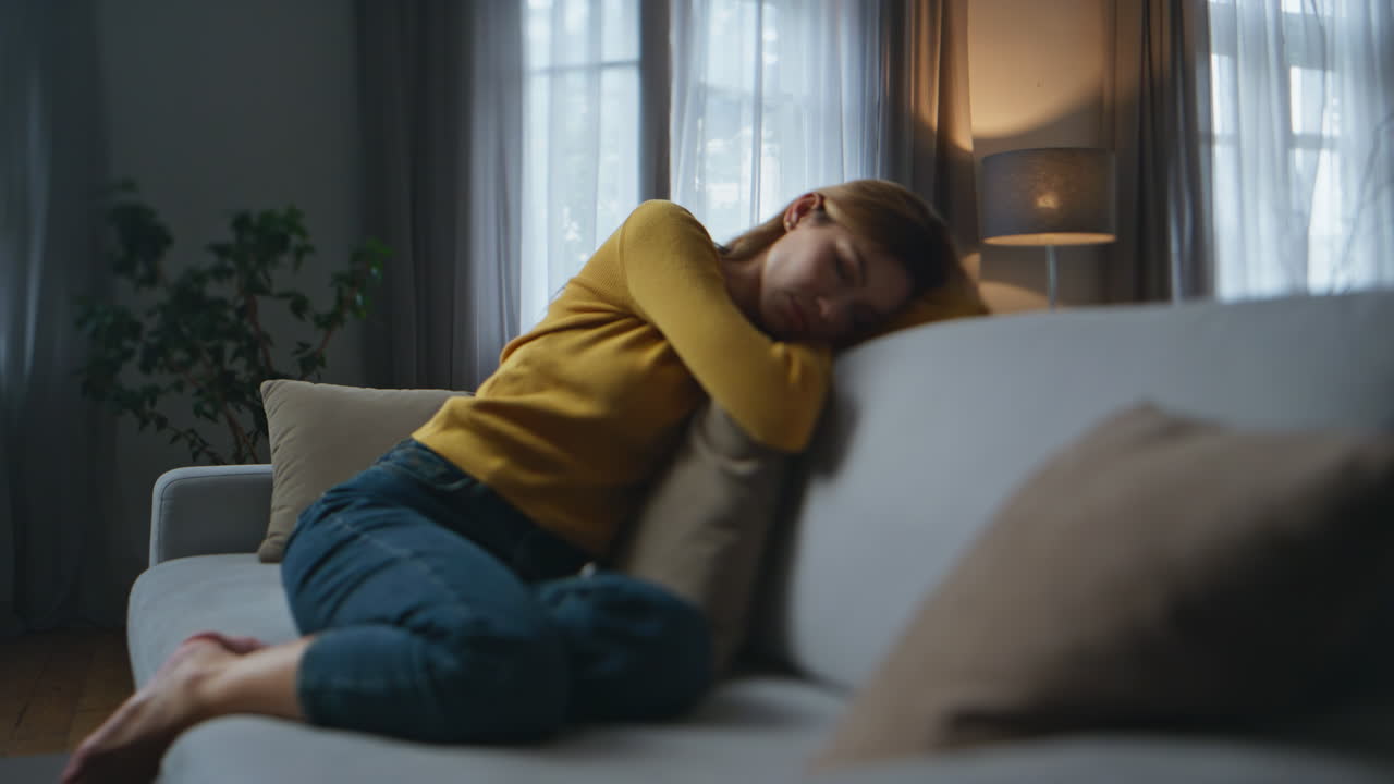 Tired woman sleeping sofa evening empty flat. Apathetic bored girl feeling sad