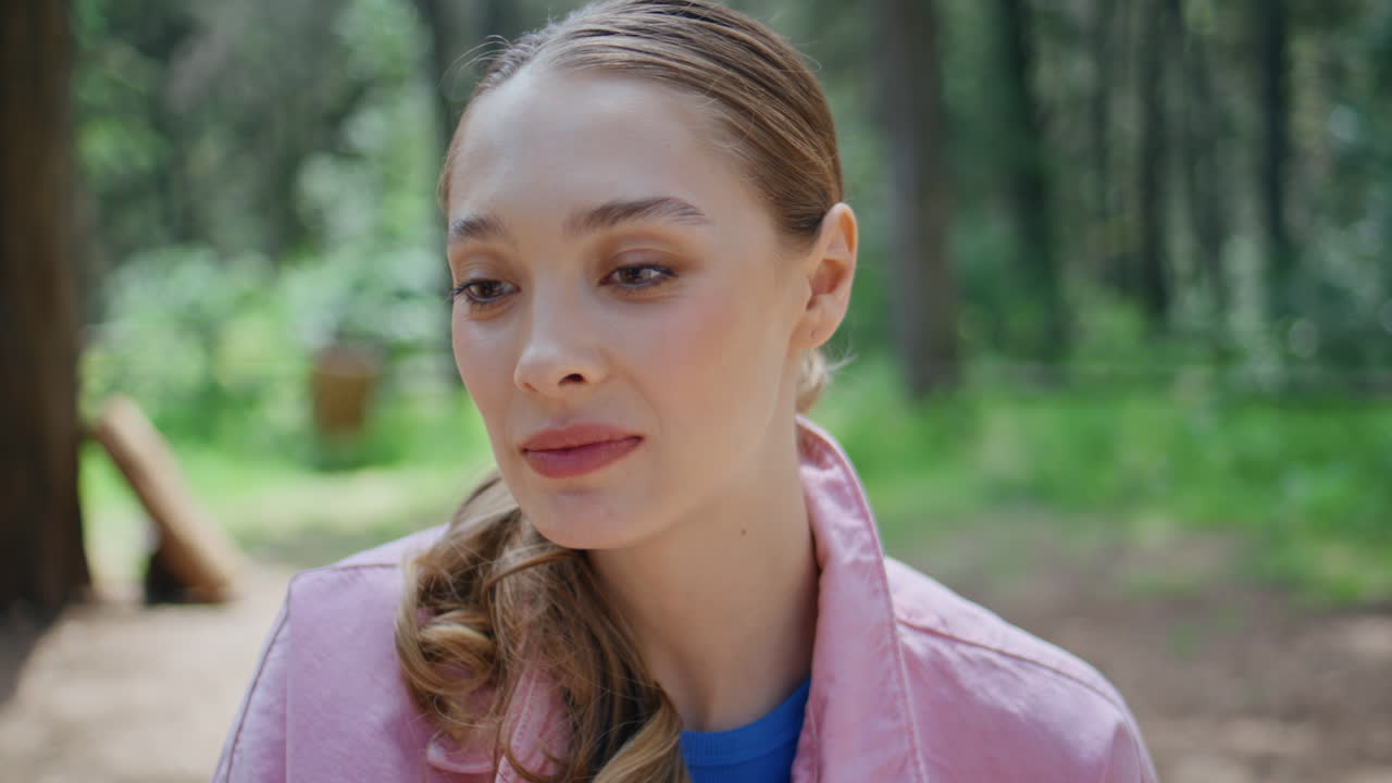 Smiling girl toasting beer bottle with unknown friends at park picnic closeup