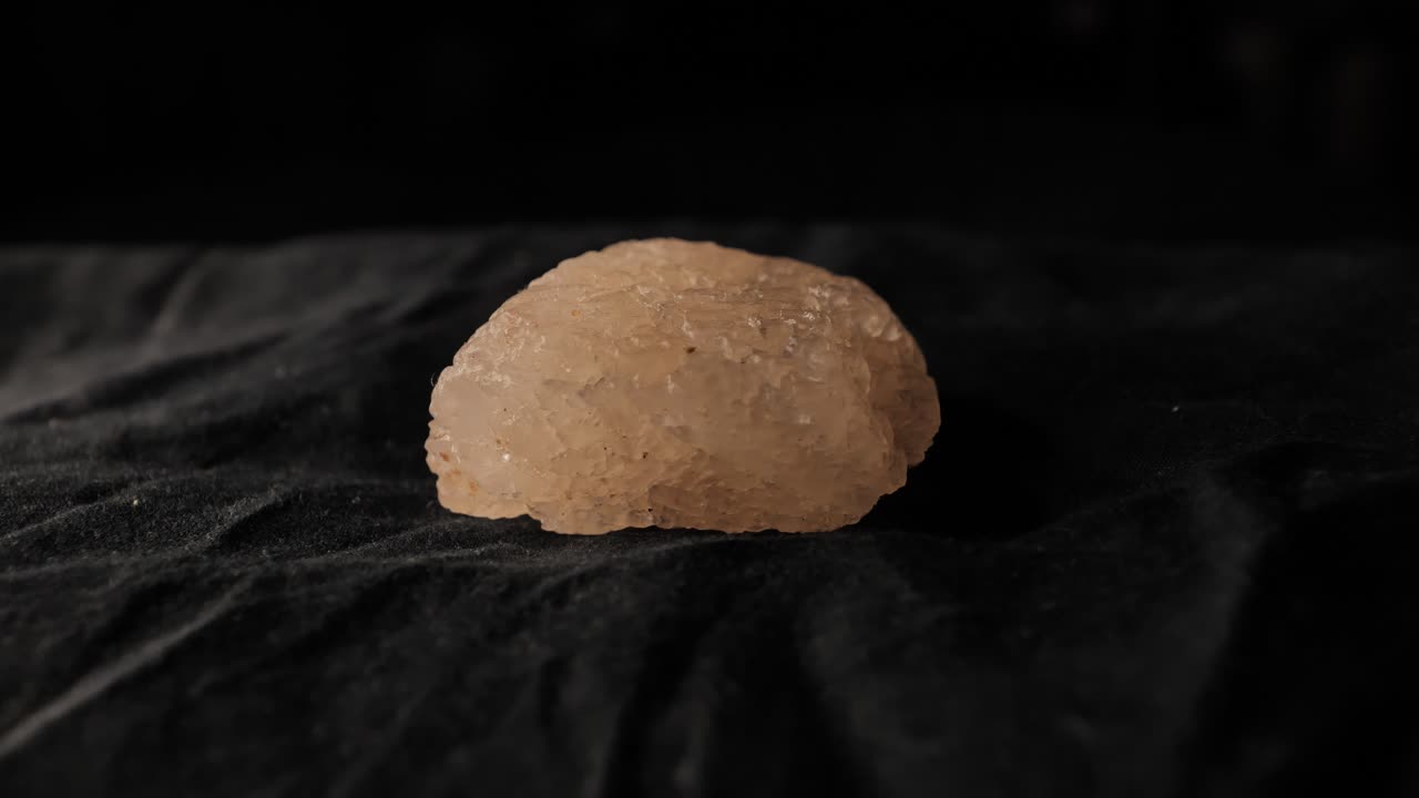 Rough Crystal Rock Rotates on Cloth in Dim Light Dramatic Composition