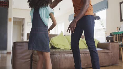 padre y hija afroamericanos bailando en casa
