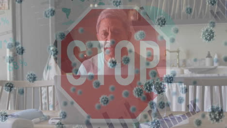animación de señales de alto y células de virus sobre un hombre biracial triste que usa una computadora portátil en casa