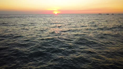 drone volando sobre un hermoso océano azul durante la puesta de sol