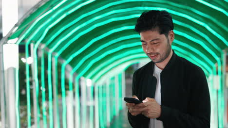 man using phone in illuminated tunnel