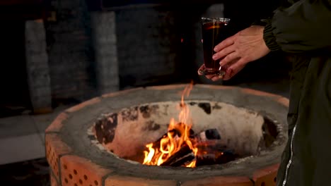 woman with drink by a fireplace