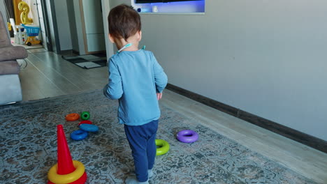 cute caucasian toddler assembles toy pyramid. little boy plays at home with his toys.