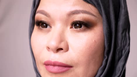 closeup shoot of adult attractive muslim female in hijab looking forward and turning to camera with isolated background